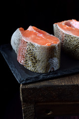 Raw red fish steaks on a slate board against black background