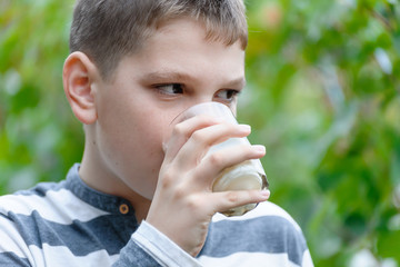 Boy drinks milk from a glass, portrait, focus on eyes