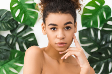 Skin beauty. Afro lady posing over tropical leaves