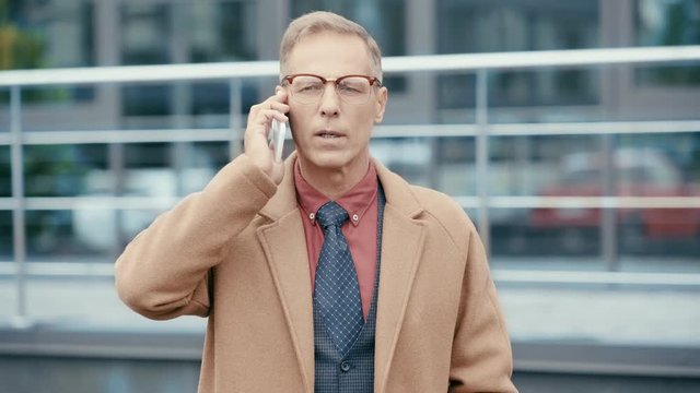 businessman in coat talking on smartphone 