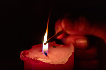 Kinderhand spielt mit dem Feuer mit Kerzen und Kerzenschein in der Dunkelheit der Adventszeit mit...