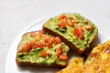 Healthy breakfast with omelette and guacamole toast on white background