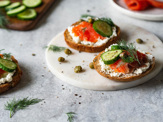 Several sandwiches on rye bread with cream cheese, salmon, fresh cucumber and spices.