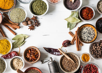 Various dry spices flat lay in small bowls on white wood background. Top view, copy space