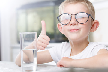 little boy in the kitchen with a glass of clean water
