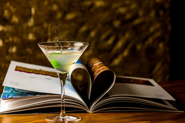martini glass with splashing cocktail and apple slice next to the journal