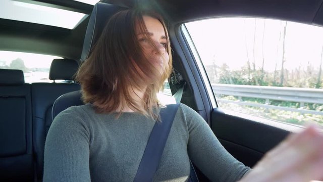 Happy redhead woman listening music in car while driving slow motion