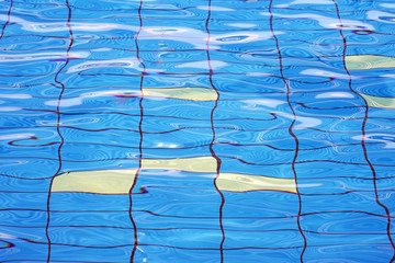 Pure blue water in the pool. Water background. Swimming pool bottom caustics ripple and flow with waves background. Water in swimming pool rippled water detail background. 