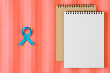 blue prostate ribbon on open notebook isolated on Living Coral background