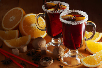 Two cups with ready mulled wine with anise, cinnamon and nuts around	