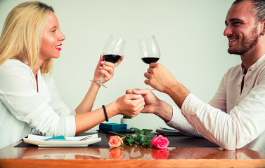 Beautiful young couple with glasses of red wine in luxury restaurant. Smiling couple drinking wine after wedding proposal..leisure, celebration, food and drinks, people and holidays concept - Image