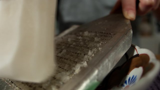 a Japanese female chef grating DAIKON (Mooli) at her home kitchen, Tokyo, Japan. July 2019. Camera fixed, extreme close up, high view,