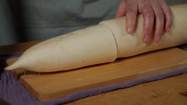 a Japanese female chef grating DAIKON (Mooli) at her home kitchen, Tokyo, Japan. July 2019. Camera fixed, close up, high view,