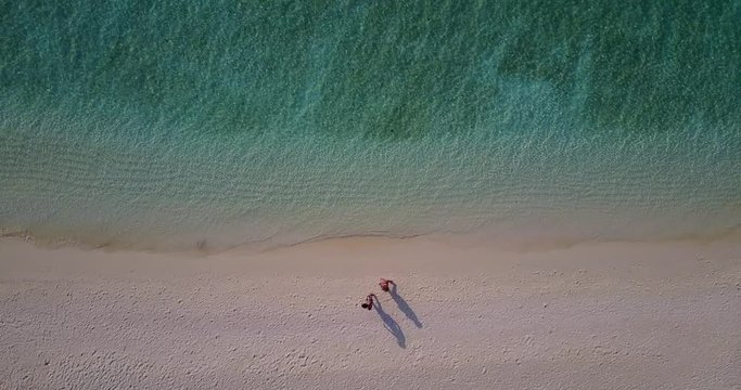 Top view from very high of a couple walking along pink sand beach before the evening in Linapacan, Philippines