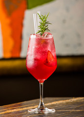 strawberry cocktail in glass with rosemary and straws
