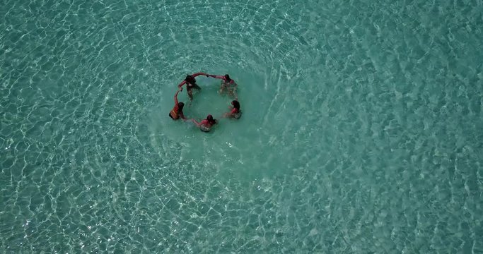 Top view of group of five young people handling hands on shallow turquoise water in Pulau Biola, Singapore