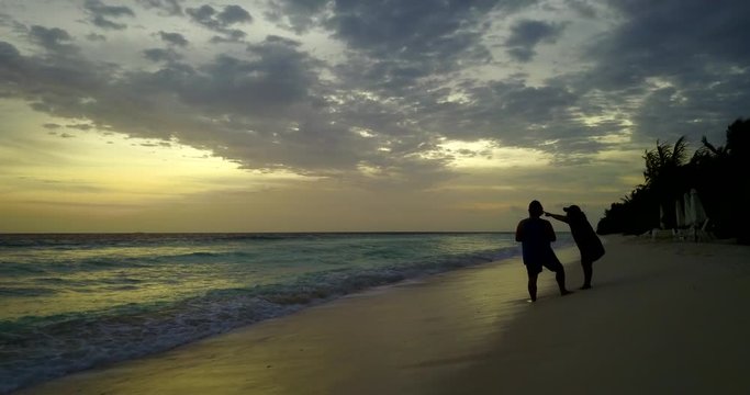 Exalted young woman enjoying romantic sunset with her boyfriend on tropical beach in Ko Lanta Yai island, Thailand
