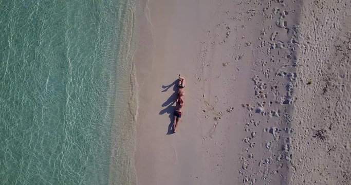 Top view aerial 360 of couple lying on the beach sand early morning in Chagos Archipelago