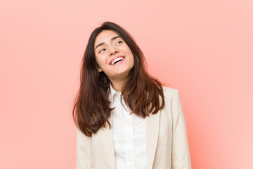 Young brunette business woman against a pink background relaxed and happy laughing, neck stretched showing teeth.
