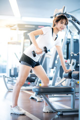 Fototapeta na wymiar Happy beautiful asian woman smiling and lifting dumbbells cheerful in sports fitness gym , excersie and healthcare concept