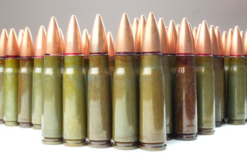 Lots of green and one brown 7.62 mm cartridges for Kalashnikov assault rifle. Selective focus....