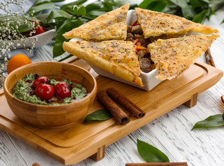 bowl of azerbaijani roasted meat cooked with dried furits topped with crusty flatbreads