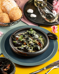 cast iron pan of mussels in cream sauce garnished with fresh herbs