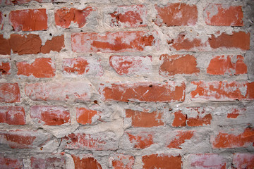 Textured wall of red brick with a textured, uneven cement seams