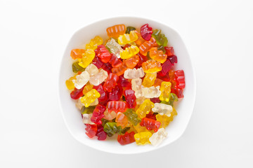 colorful jelly candy in a bowl on white background, view from above