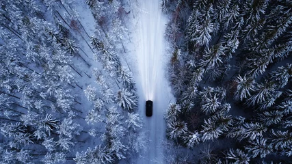 Luftaufnahme eines Autos auf der Winterstraße im Wald. Luftaufnahmen von verschneiten Wäldern mit Auto auf der Straße. Luftbild. Auto in Bewegung © raland