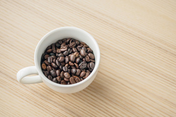 fresh roasted coffee beans in white cup on wood table