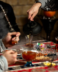 man pouring tea into armudu glass in azerbaijani traditional tea setup