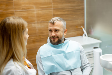 Female dentist and handsome man as a patient during a medical consultation at the dental office