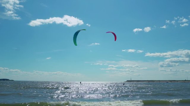 Panoramic views of young people kitesurfing in the tropical blue ocean. Kitesurfers enjoying wind power. Kitesurfing on a tropical island. 4k footage.