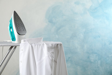 Iron and shirt on ironing board, space for text