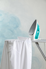 Iron and shirt on ironing board, space for text