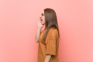 Young student woman wearing eyeglasses shouting and holding palm near opened mouth.