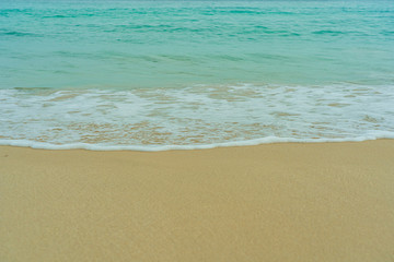 The waves of the turquoise sea swept into the sand beach.
