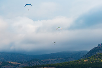 Paragliders couple on a background of clouds and mountains, three paragliders