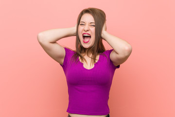 Young hispanic woman against a pink wall covering ears with hands trying not to hear too loud sound.
