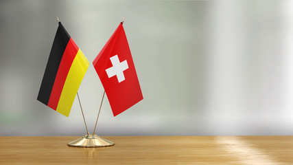 Swiss and German flag pair on a desk over defocused background  - 297861257