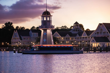 Orlando, Florida. October 11, 2019. Taxi boat, lighthouse and villas on colorful sunset background...