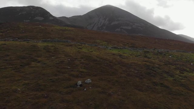 Aerial: Flying high to Croagh Patrick mountain top above creek and fields