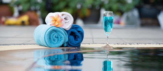 Relaxing times concept ,blue towel with cocktail beside the pool with a beautiful frangipani flower.