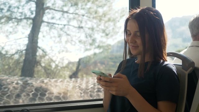 Enjoying travel tourist concept. Young pretty woman tourist traveling by the train or bus sitting near the window using smartphone, take photo on phone