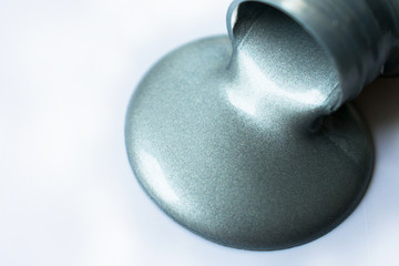  Silver paint poured from a bottle on a white background. Copy space.