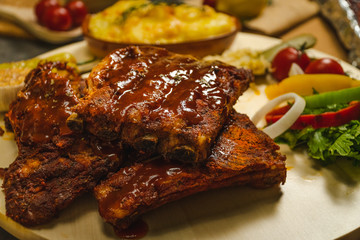 Roasted pork ribs BBQ with baked potato and salad on wooden plate