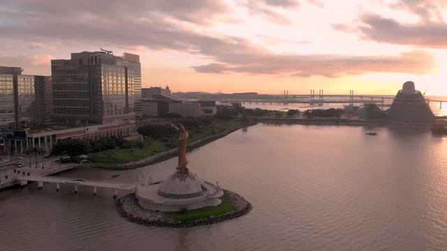 Slow pan shot of Macau bay area with Kun Iam statue and Macau Science Centre in front of beautiful golden sunrise