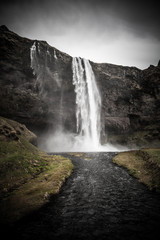 Famous Iceland waterfalls with a clean water on a stony rocky mountain landscape. Toned