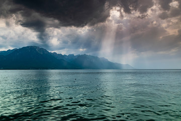 Landscape of Alps mountains,lake Geneva,dark clouds with sun rays before the rain.Shot taken from the shore of the lake in Montreux, Switzerland.